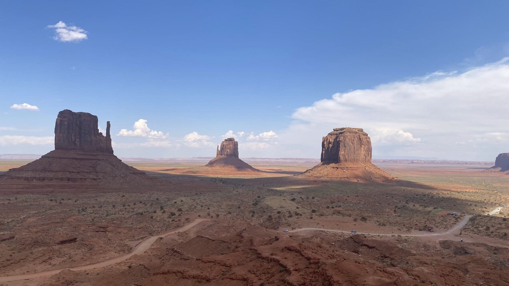 Formações rochosas icônicas no deserto de Monument Valley, sob um céu azul com nuvens esparsas, entre Utah e Arizona, nos Estados Unidos.